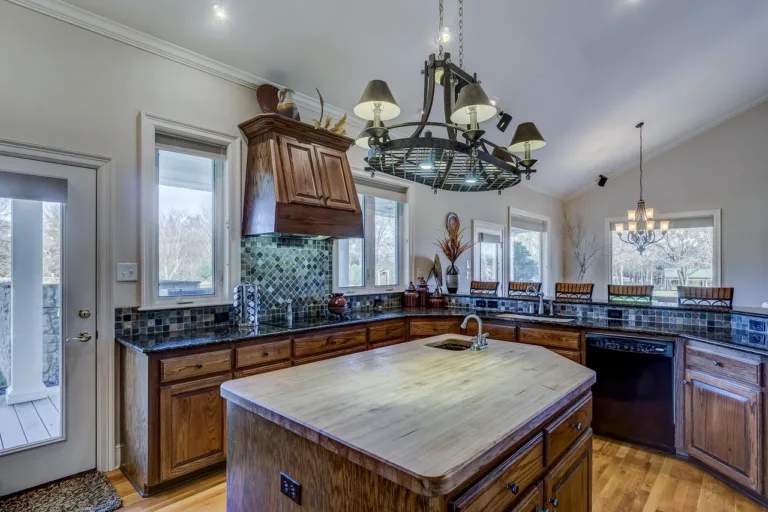 A picture of a kitchen with lighting & cabinets in a brown color theme
