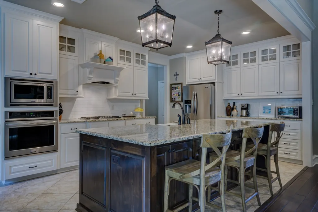 A picture of a kicthen with lighting & cabinets in a white and black theme with granite