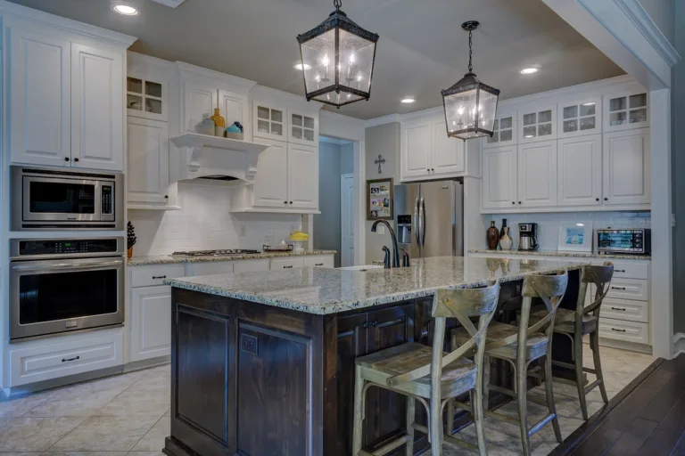 A picture of a kicthen with lighting & cabinets in a white and black theme with granite