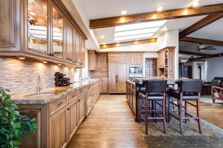 A picture of a kicthen with lighting & cabinets in a brown hardwood theme