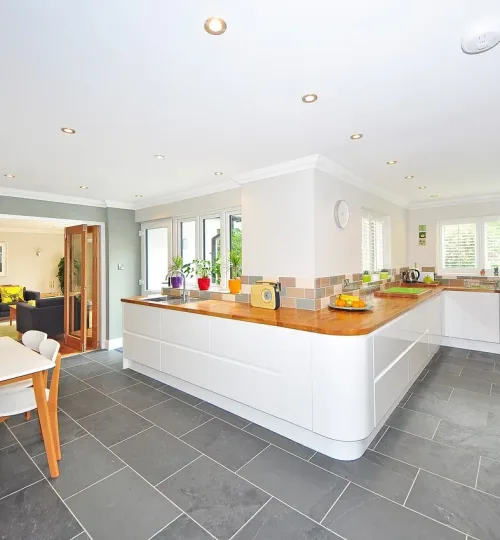 A picture of a kicthen with a white theme and grey flooring