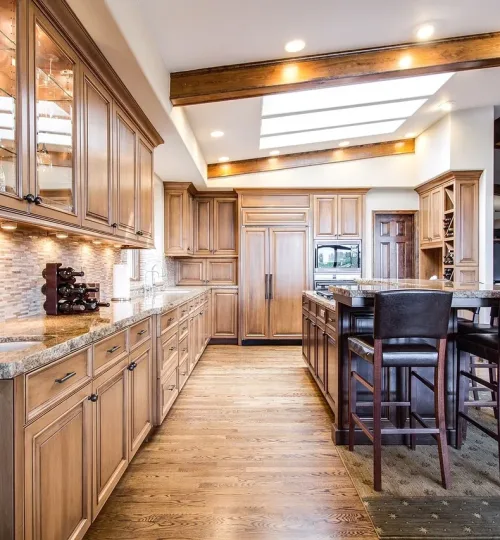 A picture of a kicthen with lighting & cabinets in a brown hardwood theme