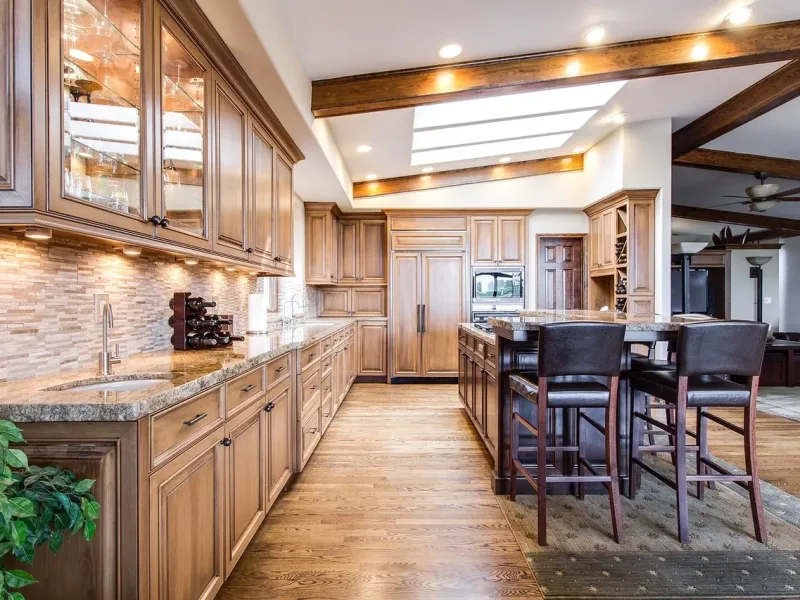 A picture of a kicthen with lighting & cabinets in a brown hardwood theme