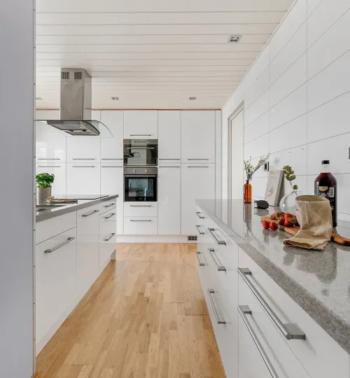 long kitchen with hardwood floor and white cabinetry